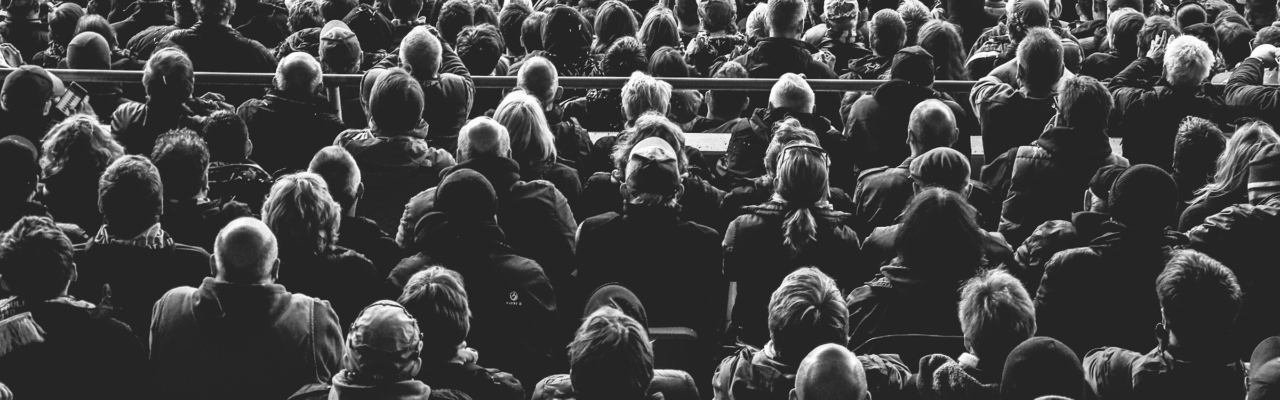 Black and white photo of people sitting in a stadio